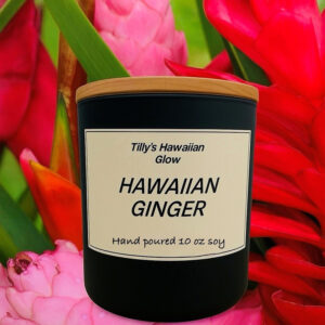 Tilly's Hawaiian Glow Hawaiian Ginger 10 oz hand-poured black soy candle with wooden lid, against a background of red and pink ginger flowers.