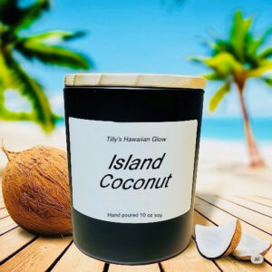 Tilly's Hawaiian Glow Island Coconut 10 oz hand-poured black soy candle with wooden lid, whole coconut, and coconut pieces on a wooden deck with a beach and palm trees in the background.