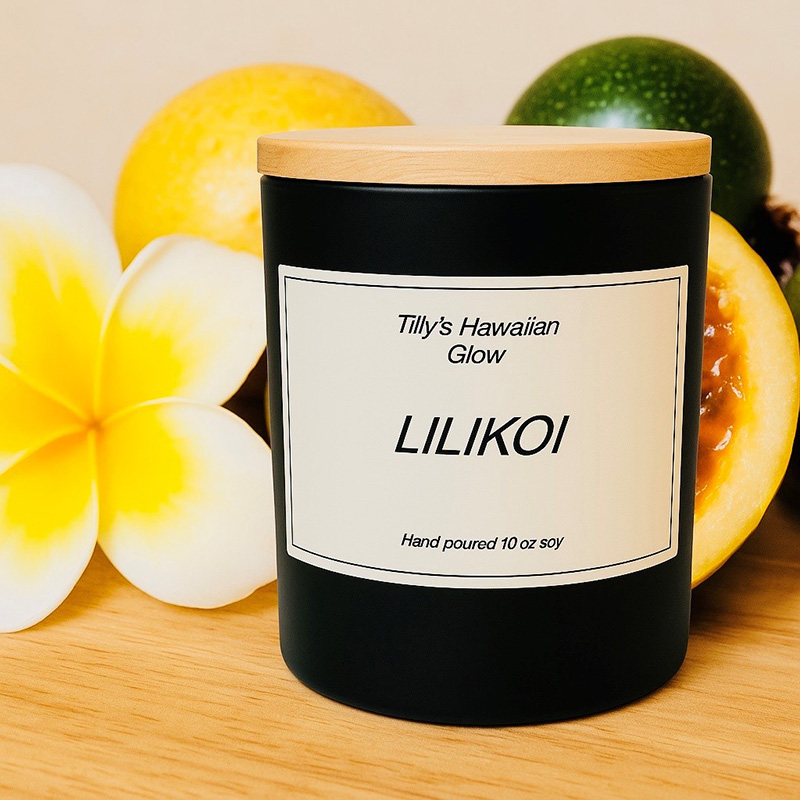 Tilly's Hawaiian Glow Lilikoi 10 oz hand-poured black soy candle with wooden lid, surrounded by whole and sliced passion fruit and yellow plumeria flowers.